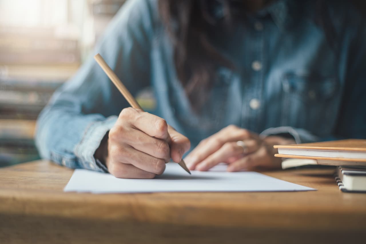 high school student holding pencil writing paper answer sheet